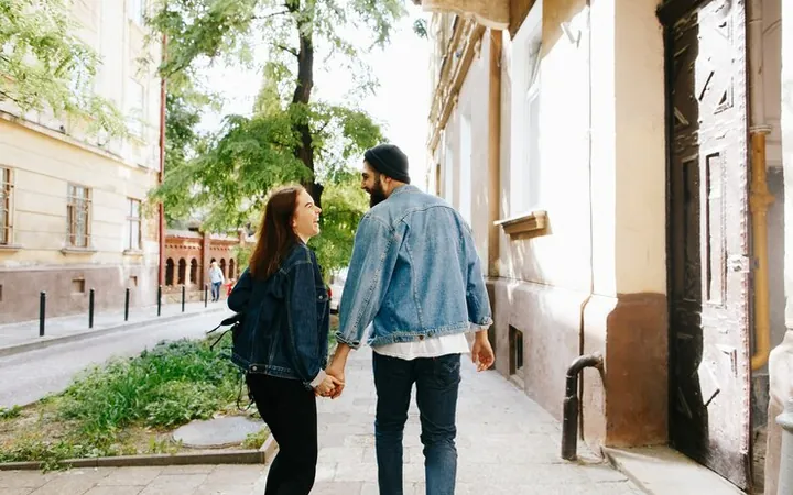 Un bărbat și o femeie se plimbă ținându-se de mână pe o stradă veche